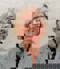 Laura Doughty, Director of Income Generation and Communications, in a grey check jacket and glasses, laughing