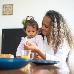 woman giving lunch to young child with Down's syndrome
