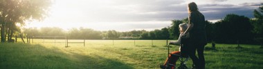woman in wheelchair and carer in a field looking into the horizon