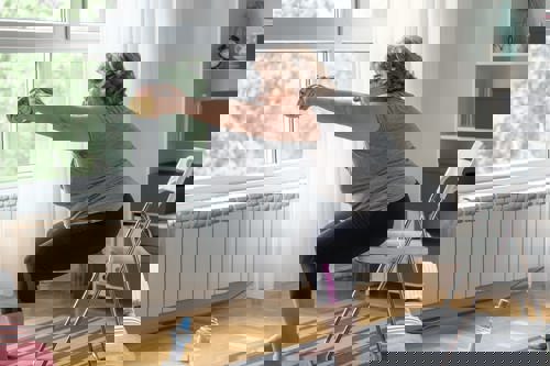 older woman doing squats on a chair