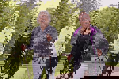 smiling women walking outdoors with walking poles