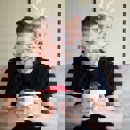 man holding a surprise gift, young child with hands over his eyes