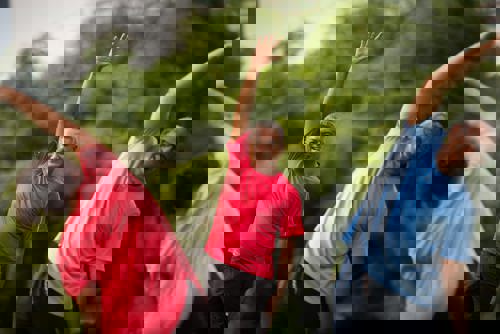 Group of three people doing stretches outdoors