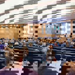 Rows of AGM attendees listening to people talking on stage