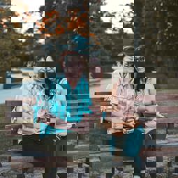 two people on a bench talking outdoors in summer